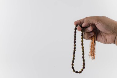 Erkek eli beyaz arka planda tahta boncuklar ya da tasbih tutuyor. Seçici odaklanma. Boşluk konseptini kopyala