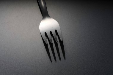 gümüş, stüdyoda gri yüzeyüzerinde bir paslanmaz çatal 