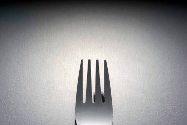 gümüş, stüdyoda gri yüzeyüzerinde bir paslanmaz çatal 