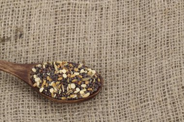 Çuval tekstilile tahta kaşık üzerine karışık çemen tohumu 