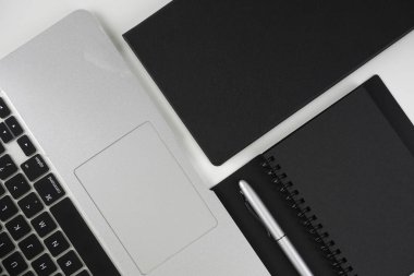 Beyaz arkaplan üzerinde siyah kitap ve gümüş kalem düz yatıyordu