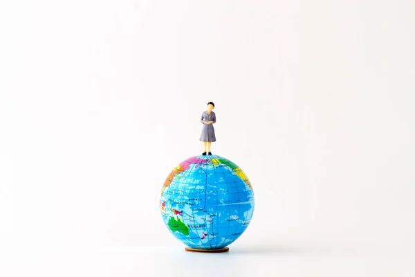 studio shot of small earth planet globe toy with woman figurine toy