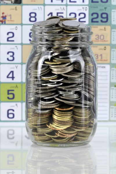 Coins in jar for saving and digital tab. Business and finance concept.