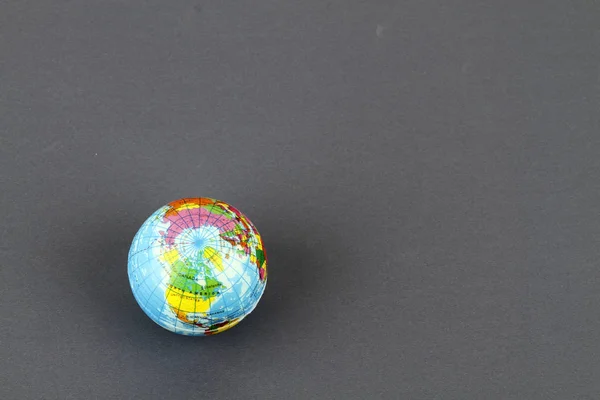 studio shot of small earth planet globe toy isolated on grey