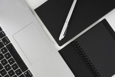 Beyaz arkaplan üzerinde siyah kitap ve gümüş kalem düz yatıyordu