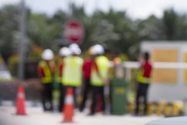 bokeh people at work with safety jackets and hard hats