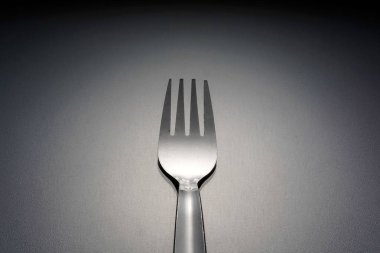 gümüş, stüdyoda gri yüzeyüzerinde bir paslanmaz çatal 