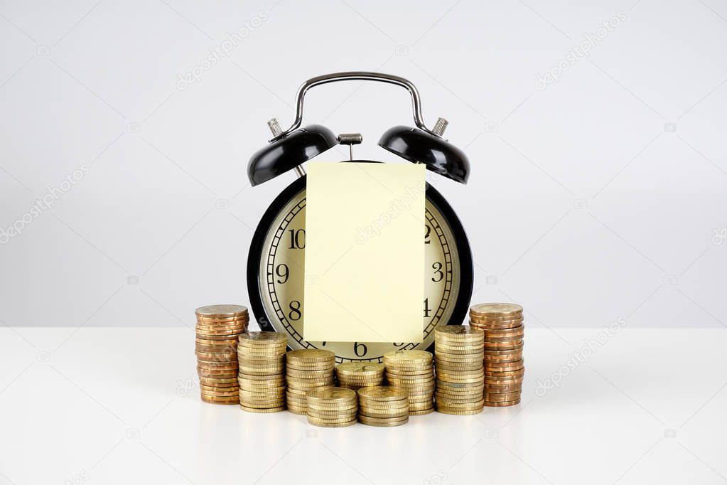 monetary salary, golden coins and analog vintage alarm clock with paper reminder sticker  
