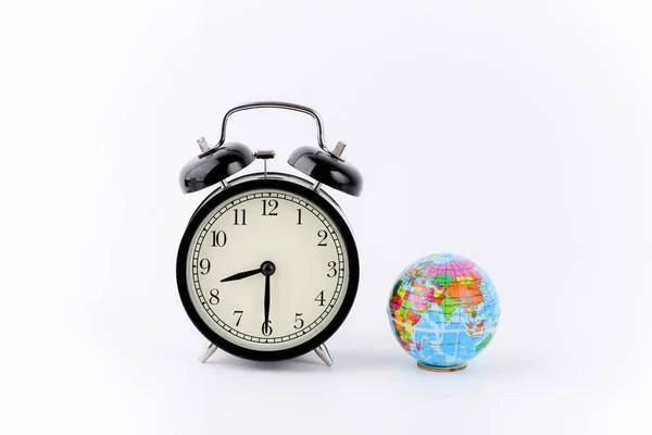 studio shot of small earth planet globe toy and old alarm analog clock time