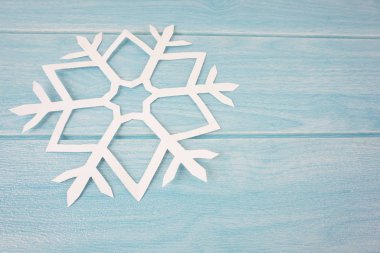 mavi ahşap masa yüzeyinde origami kağıt kar tanesi, üst görünüm 
