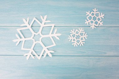 mavi ahşap masa yüzeyinde origami kağıt kar taneleri, üst görünümü 