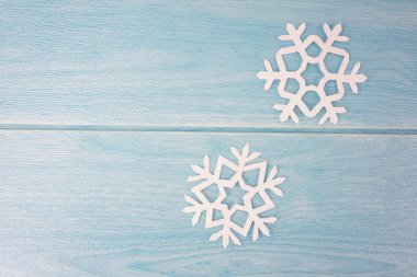 mavi ahşap masa yüzeyinde origami kağıt kar taneleri, üst görünümü 