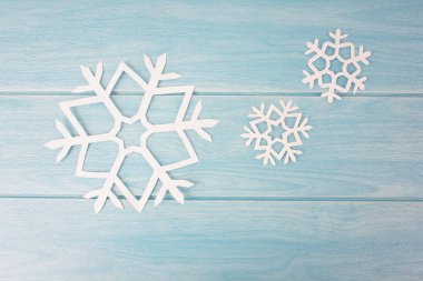 mavi ahşap masa yüzeyinde origami kağıt kar taneleri, üst görünümü 
