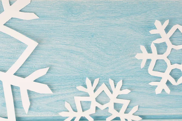 mavi ahşap masa yüzeyinde origami kağıt kar taneleri, üst görünümü 