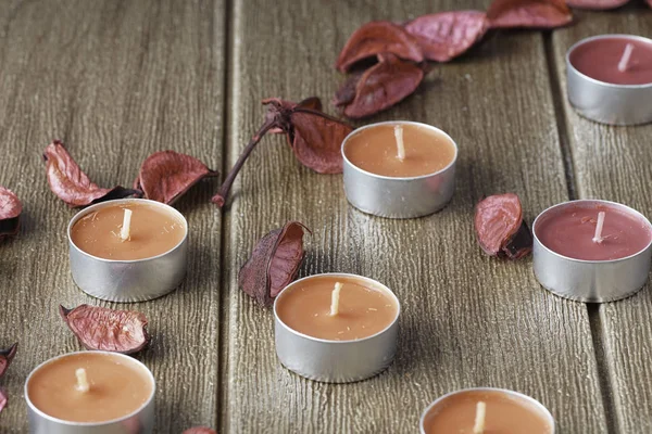 Tealight Candles and dry petals on wooden table