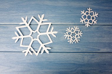 mavi ahşap masa yüzeyinde origami kağıt kar taneleri, kış konsepti