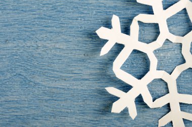 kısmi görünüm, mavi ahşap masa yüzeyinde origami kağıt kar tanesi kırpılmış parçası 