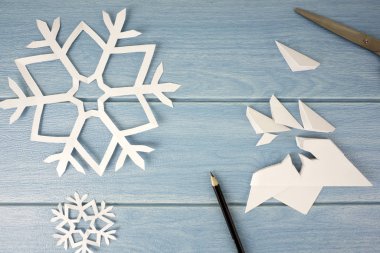 kalem ve makas ile mavi ahşap masa yüzeyinde origami kağıt kar taneleri