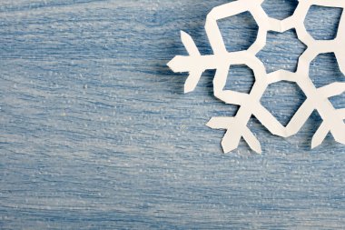 kısmi görünüm, mavi ahşap masa yüzeyinde origami kağıt kar tanesi kırpılmış parçası 