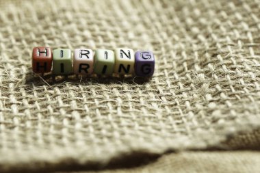burlap kumaş tekstil yüzeyinde harflerle renkli küçük boncuklar, işe kavramı 