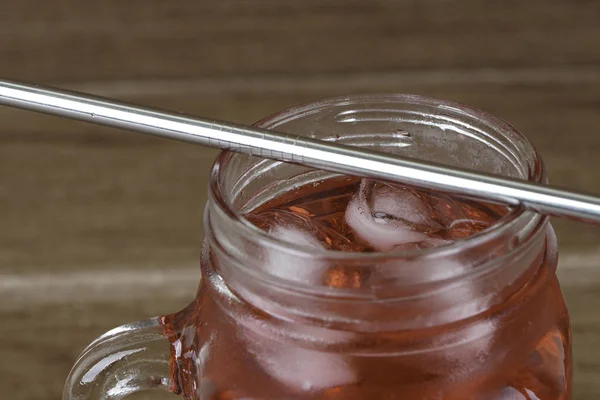 strawberry cocktail in glass mug and metallic straw on table