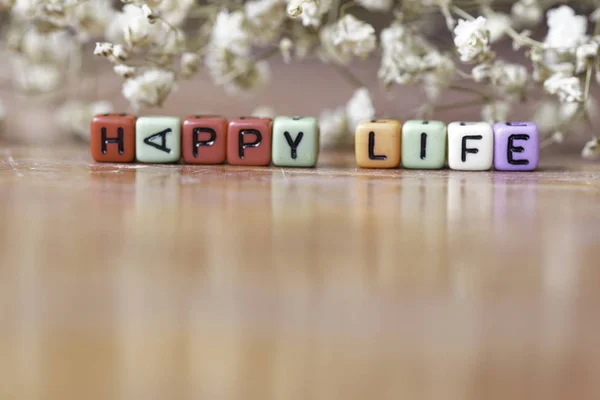 Kolorowe Małe Koraliki Literami Szczęśliwe Życie Suche Białe Kwiaty Tle — Zdjęcie stockowe