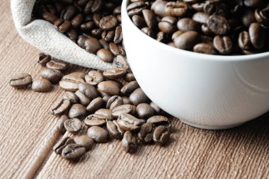 çanta ve fincan ile masada kahverengi kavrulmuş kahve çekirdekleri 