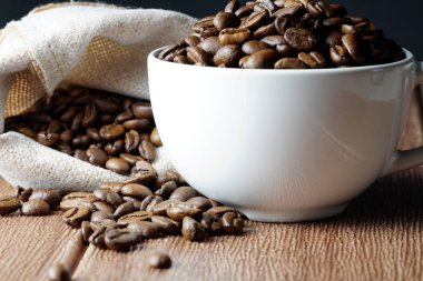 çanta ve fincan ile masada kahverengi kavrulmuş kahve çekirdekleri 