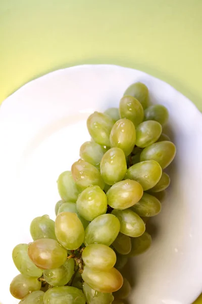 Bos Van Groene Druiven Een Witte Plaat Een Gele Achtergrond — Stockfoto