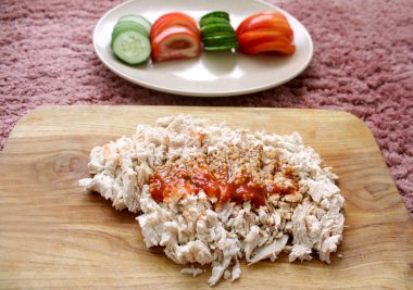 haşlanmış tavuk eti sos ve baharat ile bir tahta üzerinde dilimlenmiş, doğranmış sebze bir tabak ile