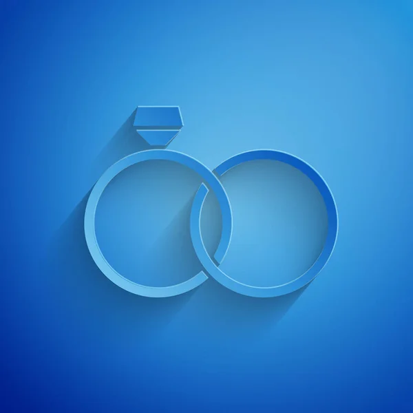 Paper cut Wedding rings icon isolated on blue background. Bride and groom jewelery sign. Marriage icon. Diamond ring icon. Paper art style. Vector Illustration