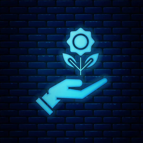 Glowing neon Hand holding flower icon isolated on brick wall background. Seed and seedling. Planting sapling. Ecology concept. Vector Illustration