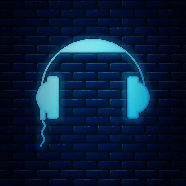 Icono de auriculares de neón brillante aislado en el fondo de la pared de ladrillo. Signo de auriculares. Concepto para escuchar música, servicio, comunicación y operador. Ilustración vectorial — Vector de stock