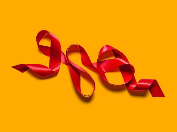 Червона атласна шовкова стрічка ізольована на жовтому фоні — стокове фото