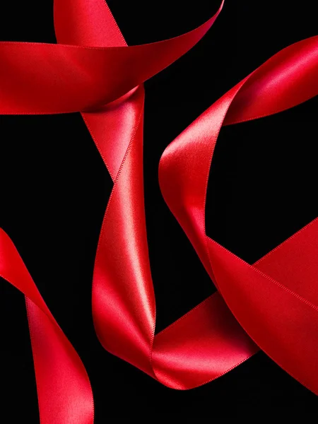 Крупним планом червона атласна абстракція шовкової стрічки ізольована на чорній спині — стокове фото