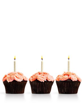 Aydınlatılmış mumları olan bir sıra kek.