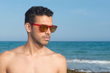 Yaz aylarında güneş gözlüğü ile denize yakın Beautiul adam