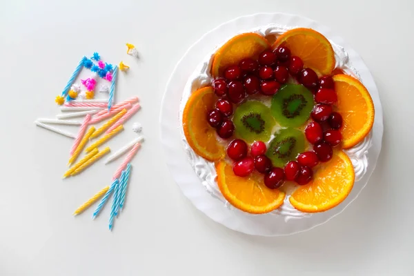 Dulce pastel sabroso con crema, fruta fresca y jalea. Velas retorcidas esparcidas alrededor — Foto de Stock