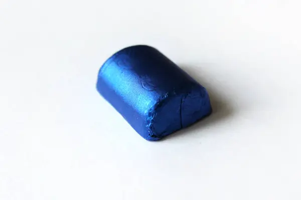 Bonbons au chocolat enveloppés dans une feuille bleue isolée sur une surface blanche — Photo