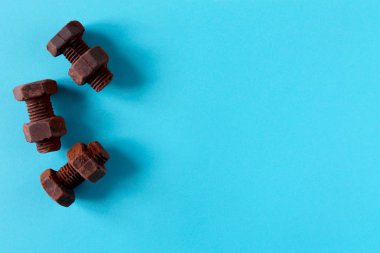 Göğe maviarka planda izole edilmiş çikolatadan yapılmış paslı cıvatalar ve somunlar