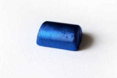 Beyaz yüzeyde izole mavi folyo sarılmış çikolata şeker