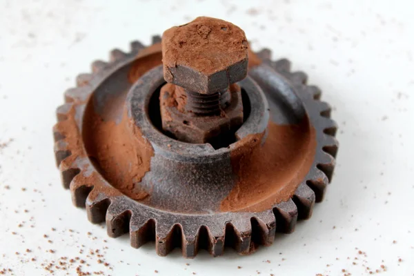 Rusty bolt, nut and gear wheel made of chocolate isolated on white background