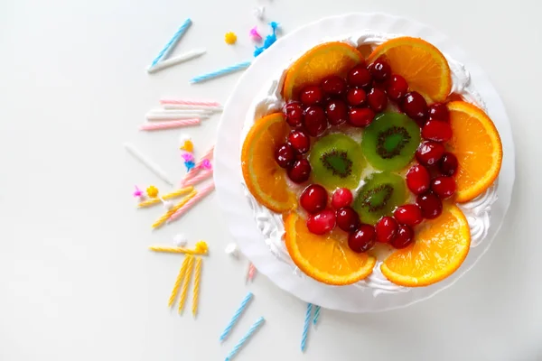 Dulce pastel sabroso con crema, fruta fresca y jalea. Velas retorcidas esparcidas alrededor — Foto de Stock