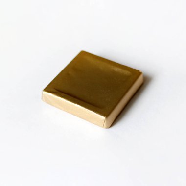 Kare çikolata şeker beyaz yüzeyde izole altın folyo sarılmış