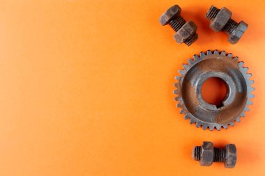 Paslı cıvatalar, somunlar ve dişli tekerlek çikolata dan yapılmış turuncu arka plan üzerinde izole