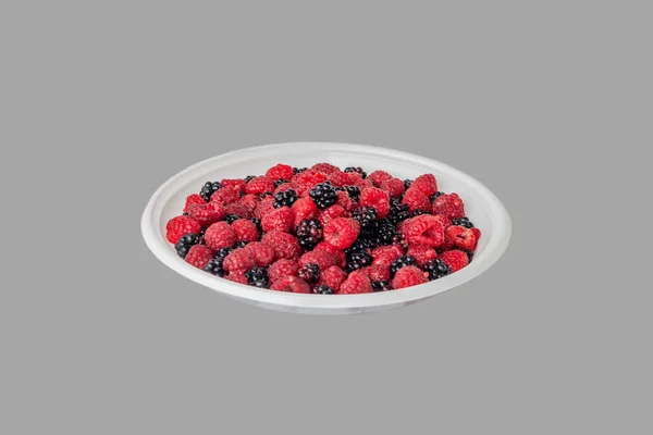 Framboises et mûres fraîches sur une assiette en plastique blanc. Sentier de coupe . — Photo