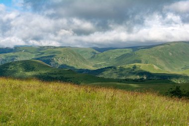 Yaz aylarında mavi gökyüzü ve bulutlar ile güzel bir güneşli bir günde çiçek açan çayır ve dağlar ile pastoral alp dağ sahne güzel görünümü.