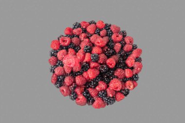 Gri bir arka plan üzerinde bir yığın taze ahududu ve böğürtlen. Kırpma yolu