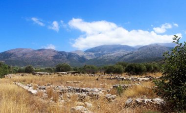 Dağ manzarası: taşlar ve kurutulmuş çimenler, ağaçlar, dağlar ve gökyüzü. Girit. Yunanistan. Turizm. Seyahat. Yaz. Rahatlama. Tatil