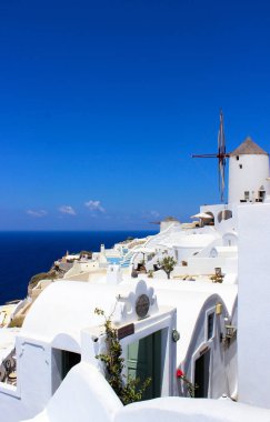 Yaz manzarası: beyaz badanalı evler, bir değirmen ve deniz. Santorini Adası Yunanistan. Seyahat. Turizm. Tatil Gevşeme.